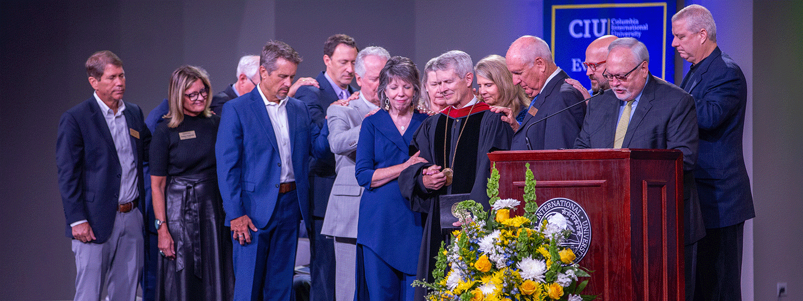 With his wife Debby at his side, new CIU President Dr. Bill Jones is surrounded by the Board of Trustees as his pastor Dr. Don Brock leads in a prayer of investiture. (Photo by Seth Berry)