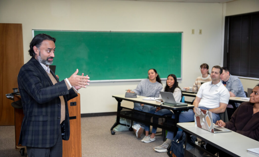 A professor speaks to a engaged group of graduate students seated at desks in a CIU classroom