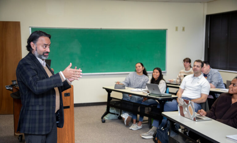 A professor speaks to a engaged group of graduate students seated at desks in a CIU classroom