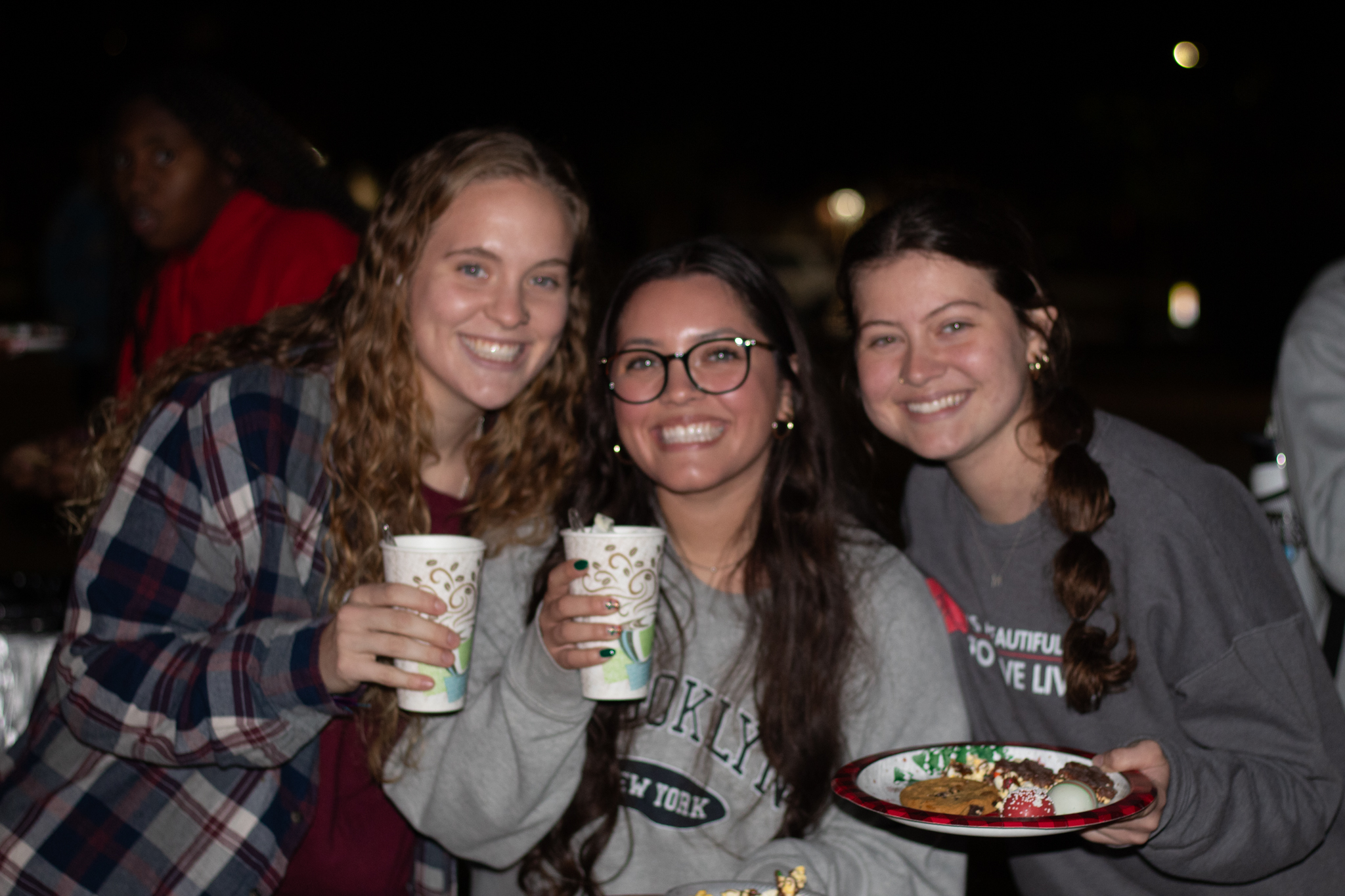 Three students drink hot chocolate during Christmas on the Quad